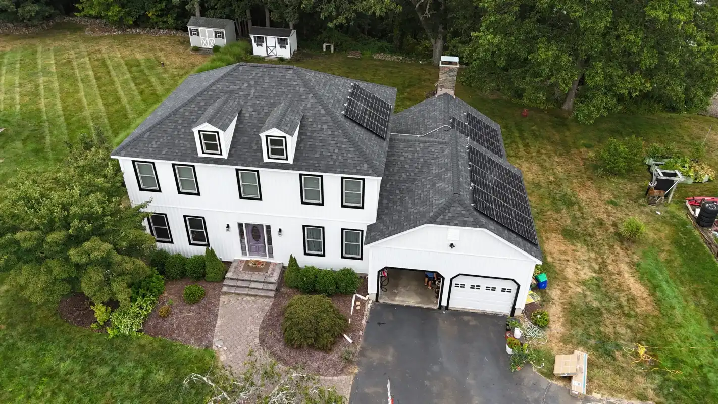 Aerial view of a white house with a new grey shingle roof