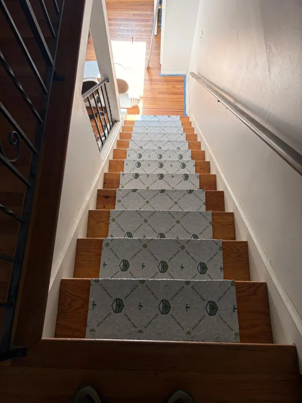 Wooden staircase with grey patterned carpet runners and white walls